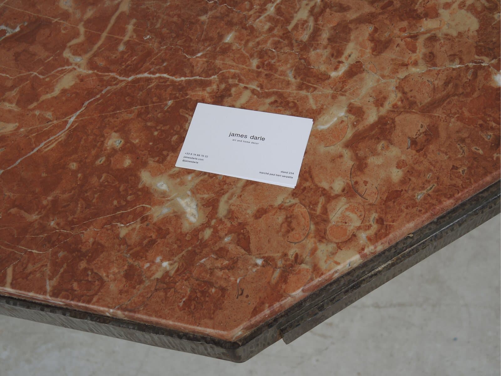 James Darle’s business card on a red marble tabletop