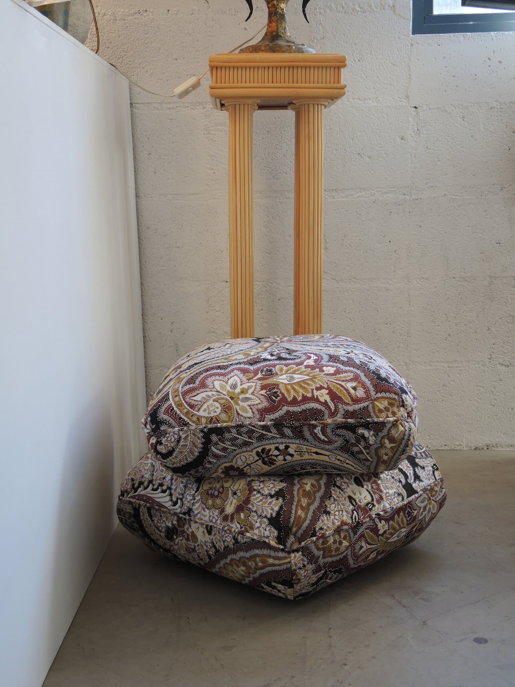 Two patterned floor cushions stacked in front of a wooden stand