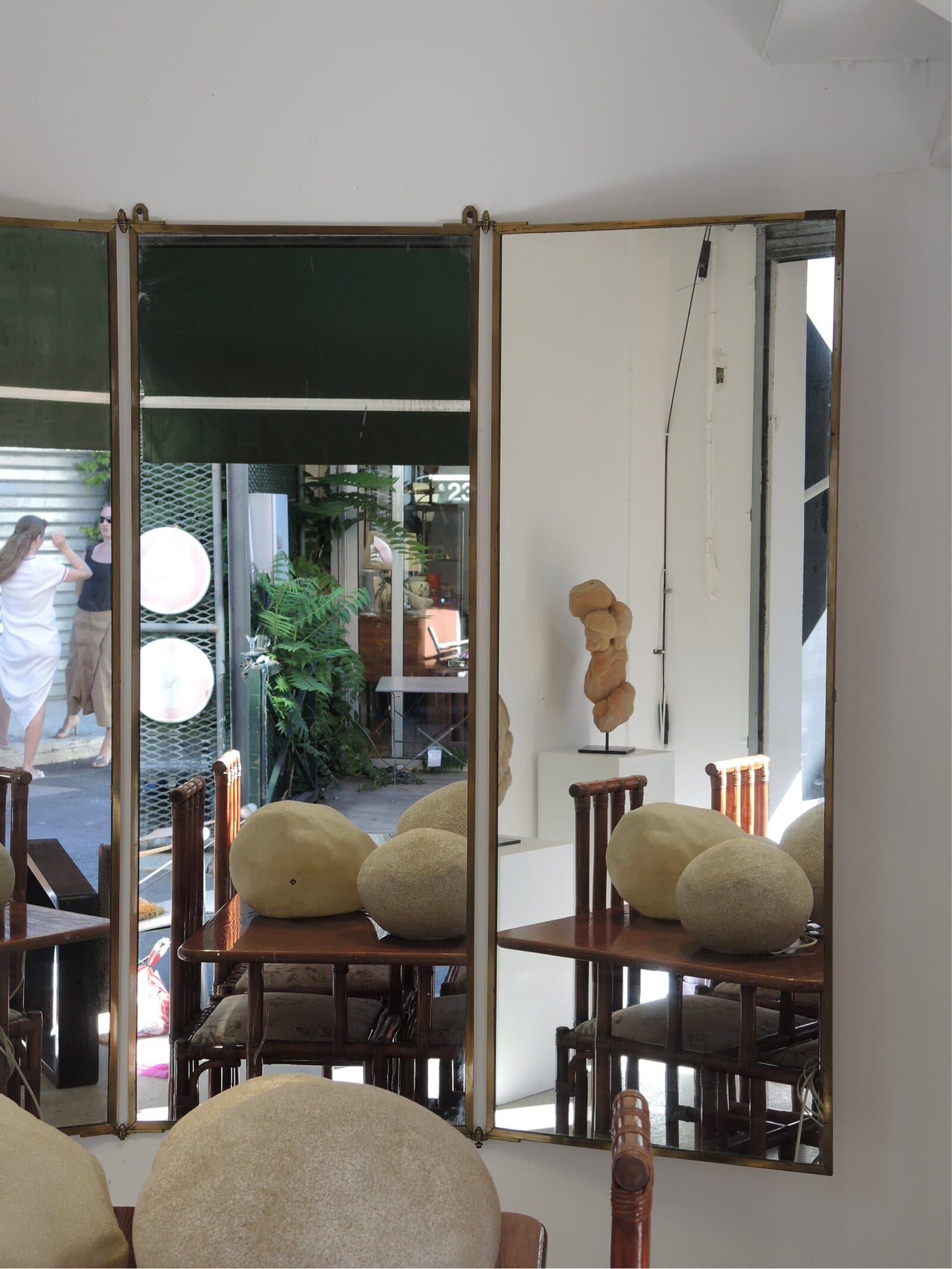 A three-panel mirror reflecting the stand and the alley outside